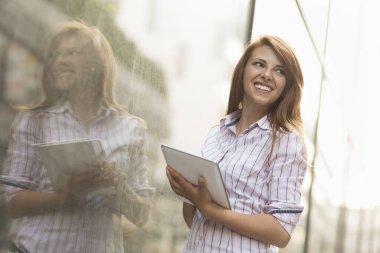Ofis dışında tablet bilgisayarında çalışan genç bir iş kadını.