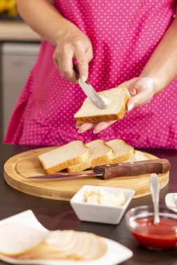 Kadın ellerinin ekmek diliminin üzerine tereyağı sürmesi kahvaltıda sandviç makinesinde sıcak sandviç yapan kadın. Bıçağın ucuna odaklan.