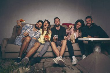 Bir grup genç arkadaş çatıdaki terasta film izliyor, pizza yiyor, bira içiyor ve eğleniyorlar.