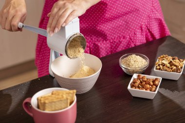 Bisküvi öğütme makinesinde bisküvi öğüten bir kadının yüksek açılı görüntüsü. Öğütme makinesindeki öğütülmüş bisküvilere odaklan.