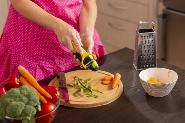 Taze sebze salatası yapmak için salatalık soyarken kadın elinin salatalık dilimleme makinesi kullanması.