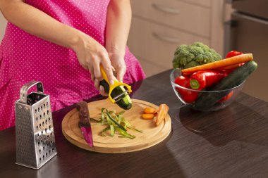 Taze sebze salatası yapmak için salatalık soyarken kadın elinin salatalık dilimleme makinesi kullanması.