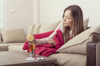 Hasta kadın yüksek ateş ve grip yüzünden yatakta yatıyor, çayına limon suyu sıkıyor..