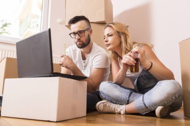 Birbirine aşık genç bir çift yeni evlerinin zemininde oturmuş yeniden dekore etmeyi ve meyve suyu içmeyi planlıyorlar.