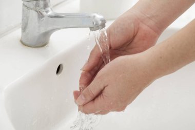 Ellerini yıkayan bir kadına yaklaş. Ellere odaklan.