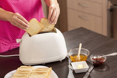 Kadın elinin tost makinesine ekmek dilimleri koyması kahvaltıda kızarmış ekmek yapması.