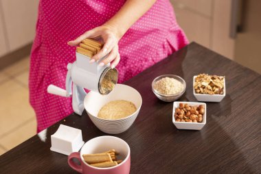 Bisküvi öğütme makinesine bisküvi koyan, kek yapmak için malzeme hazırlayan bir kadının yüksek açılı görüntüsü. Öğütme makinesindeki çalılıklara odaklan.