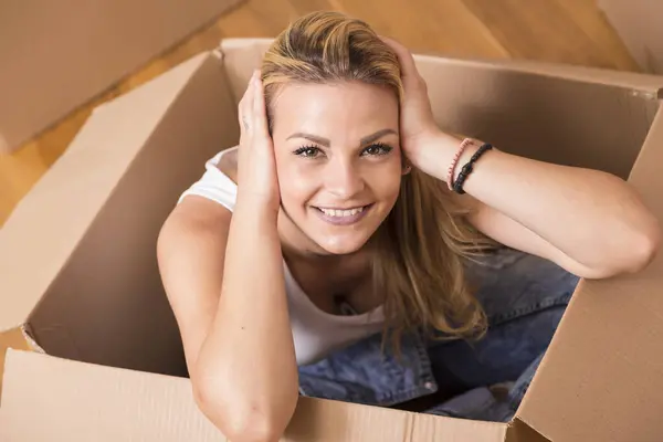 荷造りしている間の段ボール箱の中に座っている女性 — ストック写真