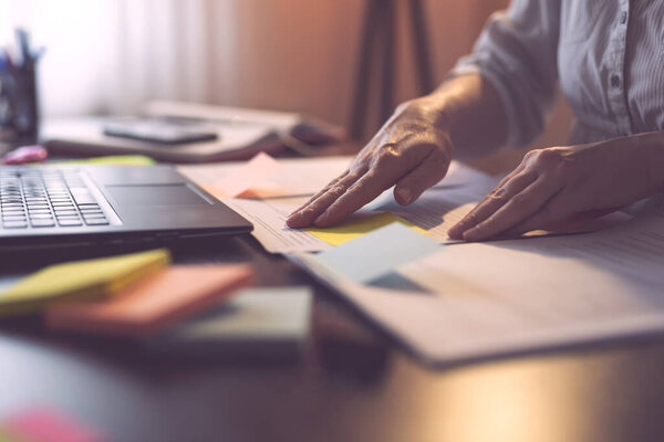 Деталь рук бизнесвумен, маркирующих страницы контракта липкими банкнотами. Сосредоточьтесь на пальцах руки, прикрепляя желтую липкую ноту