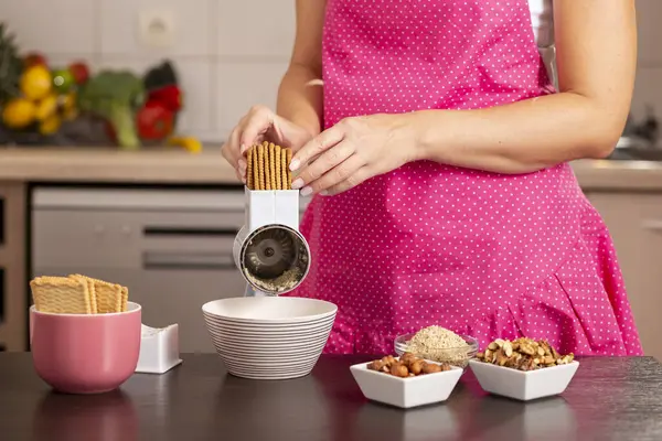 Pasta hazırlamak için bisküvi öğütücüsü kullanan bir kadın elinin ayrıntıları..