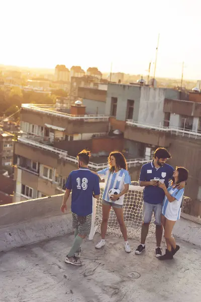 Bir grup genç arkadaş ve futbol fanatiği bir binanın çatısında takılıyor, maçtan önce bira içiyorlar.