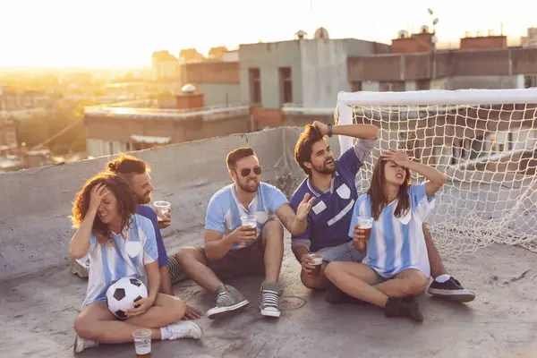 ビルの屋上でサッカーの試合を見ている若い友人のグループ 応援し ビールを飲む 真ん中の男たちに集中する — ストック写真