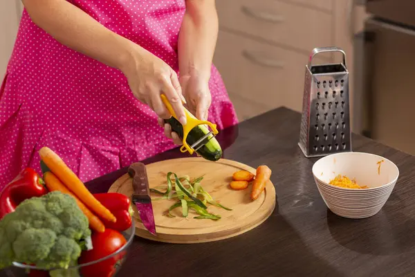 Taze sebze salatası yapmak için salatalık soyarken kadın elinin salatalık dilimleme makinesi kullanması.