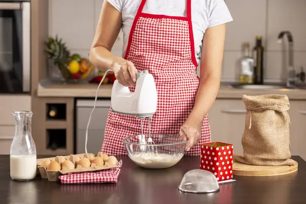 女性手持搅拌机和在厨房柜台上搅拌煎饼面团的细节 — 图库照片