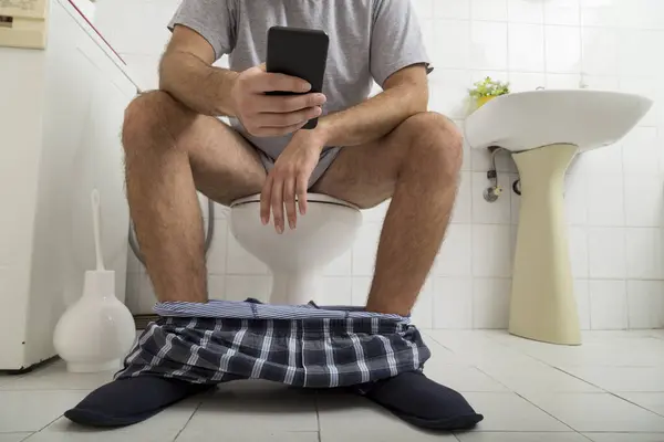 Szczegóły Człowieka Siedzącego Toalecie Piżamie Bieliźnie Dół Czytającego Gazetę Smartfonie — Zdjęcie stockowe