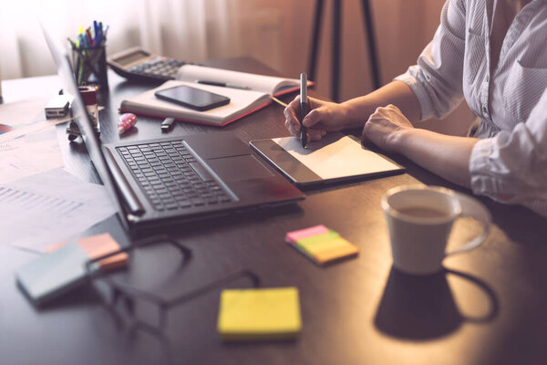 Деталь руки дизайнера, держащего ручку и рисунок на графической доске