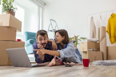 Birbirine aşık güzel genç bir çift birlikte yaşıyor, dizüstü bilgisayarla internette sörf yapıyor, internette daire dekorasyonu fikirleri arıyor.