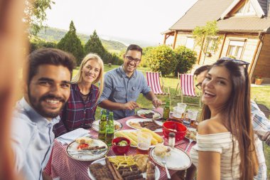 Bir grup arkadaş arka bahçede barbekü partisi veriyor, selfie çekerken eğleniyorlar.