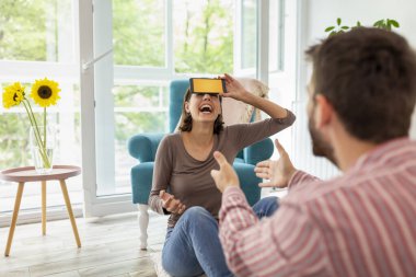 Çift evde sessiz sinema oynayarak eğleniyor, akıllı telefon uygulamasından gelen kelimeleri açıklıyor ve tahmin ediyor.