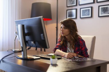 Ev ofisinde çalışan kadın grafik tasarımcısı, renk paletinden bir renk seçer