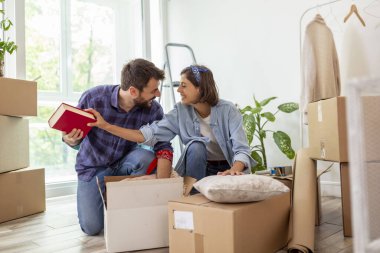 Güzel, genç ve aşık bir çift yeni dairelerine taşınırken karton kutulardan bir şeyler çıkarırken eğleniyorlar.