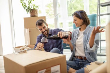 Yeni bir daireye taşınıp bir şişe şarap açarak kutlama yapan genç ve güzel bir çift.