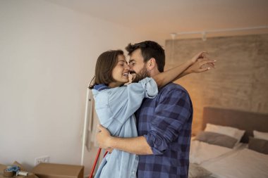 Güzel, birbirine aşık genç bir çift yeni evlerinde birbirlerine sarılıp öpüşüyorlar.