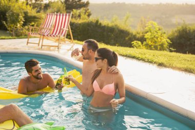 Havuz başında bir yaz partisinde bir grup arkadaş yüzme havuzunda eğleniyor, dans ediyor, kokteyl içiyor, bira içiyor ve kadeh kaldırıyor.