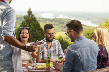 Bir grup arkadaş dışarıda barbekü yapıyor, ızgara et yiyor, bira içiyor ve eğleniyorlar.. 
