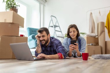 Birbirine aşık güzel genç bir çift birlikte yaşıyor, dizüstü bilgisayarla internette sörf yapıyor, internette daire dekorasyonu fikirleri arıyor.