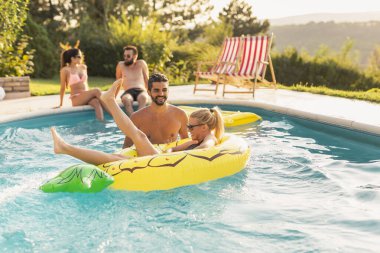 Havuz başında bir yaz partisinde aşık bir çift, güneşleniyor ve eğleniyor; kız ananas şeklinde bir şişme yatakta havuzda yüzüyor. 