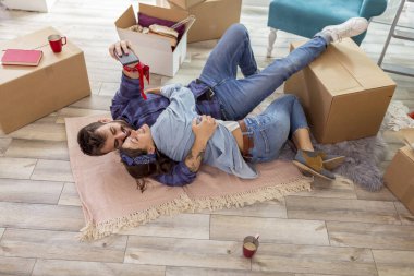 Birbirine aşık çiftlerin yeni evlerinin zemininde yatıp akıllı telefonlar kullanarak selfie çektikleri yüksek açılı görüntüler.