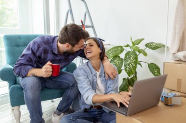 Güzel, birbirine aşık genç bir çift birlikte yaşıyor, kahve içiyor ve internette daire dekorasyonu fikirleri ararken eğleniyor. 