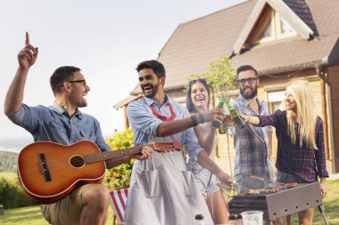 Bir grup arkadaş dışarıda barbekü partisi veriyor, bira içiyor, et pişiriyor, gitar çalıyor ve eğleniyorlar.
