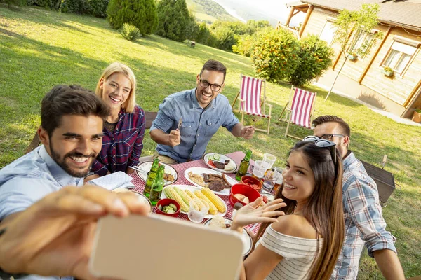 Bir grup arkadaş arka bahçede barbekü partisi veriyor, dışarıda öğle yemeği yiyor ve selfie çekerken eğleniyorlar.