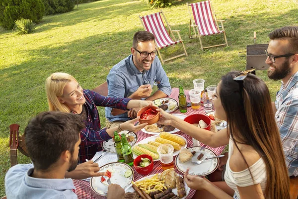 Bir grup arkadaş dışarıda barbekü yapıyor, ızgara et yiyor, bira içiyor ve eğleniyorlar. Ortadaki adama odaklan.