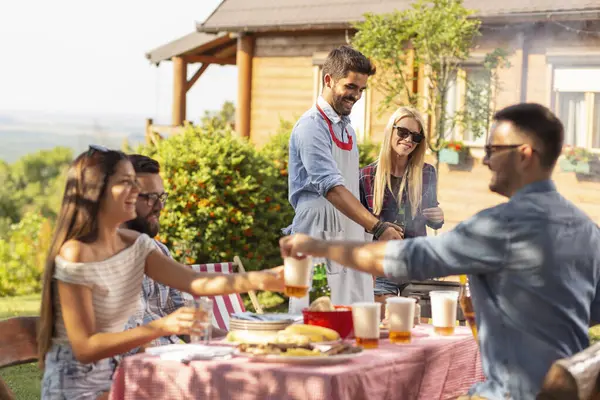 Bir grup arkadaş arka bahçede barbekü yapıyor ve güneşli bir yaz gününde eğleniyorlar. Barbekünün yanındaki çifte odaklan.