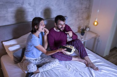 Güzel, genç aşık bir çift, yan yana oturmuş, sarılıyorlar, patlamış mısır yiyorlar ve geceleri televizyon izlerken eğleniyorlar.