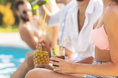 Havuz başında bir yaz partisinde bir grup arkadaş, yüzme havuzunun kenarında oturup, kokteyl ve bira içip eğleniyorlar.