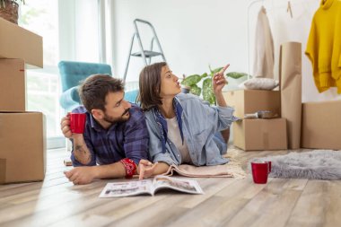 Birbirine aşık bir çift yeni evlerinde yerde yatıyor, yeniden dekore etmeyi planlıyor ve ev dekorasyonu dergilerinde iç tasarım fikirleri arıyor.