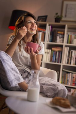 Kahvaltıda süt ve mısır gevreği yiyen güzel genç bir kadın.