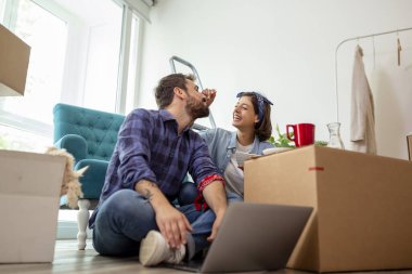 Güzel, birbirine aşık genç bir çift yeni dairelerinde karton kutuların arasında oturuyor, kahvaltı yapıyor ve dekorasyon fikirleri arıyor.