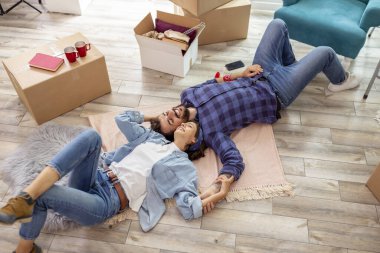 Güzel, birbirine aşık genç bir çift yeni evlerinin zemininde uzanıyor ve dinleniyor, birlikte yaşamaya devam ederken mola veriyorlar.