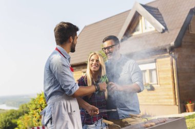 Bir grup arkadaş arka bahçede barbekü partisi veriyor, et pişiriyor, bira içiyor ve güneşli bir yaz gününde eğleniyorlar.