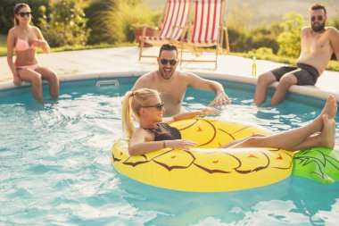 Havuz başında bir yaz partisinde aşık bir çift, güneşleniyor ve eğleniyor; kız ananas şeklinde bir şişme yatakta havuzda yüzüyor. 