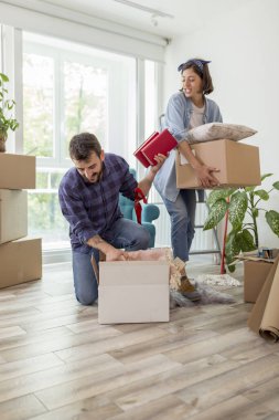 Güzel, genç ve aşık bir çift yeni dairelerine taşınırken karton kutulardan bir şeyler çıkarırken eğleniyorlar.