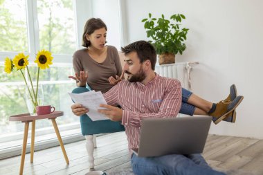Finanslarını yöneten, dizüstü bilgisayardaki banka hesaplarını inceleyen, banka kredilerini ve borçlarını hesaplayan ve çevrimiçi ödeme yapan genç ve güzel bir çift.