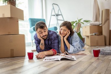 Birbirine aşık bir çift yeni evlerinde yerde yatıyor, yeniden dekore etmeyi planlıyor ve ev dekorasyonu dergilerinde iç tasarım fikirleri arıyor.