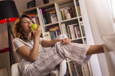 Güzel genç bir kadın kahvaltıda elma yiyor.