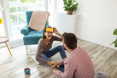 Çift evde sessiz sinema oynayarak eğleniyor, akıllı telefon uygulamasından gelen kelimeleri açıklıyor ve tahmin ediyor.